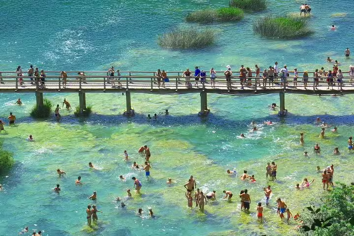 Visitors swimming near the wooden footbridge at Skradinski Buk, Krka National Park waterfalls tour Croatia