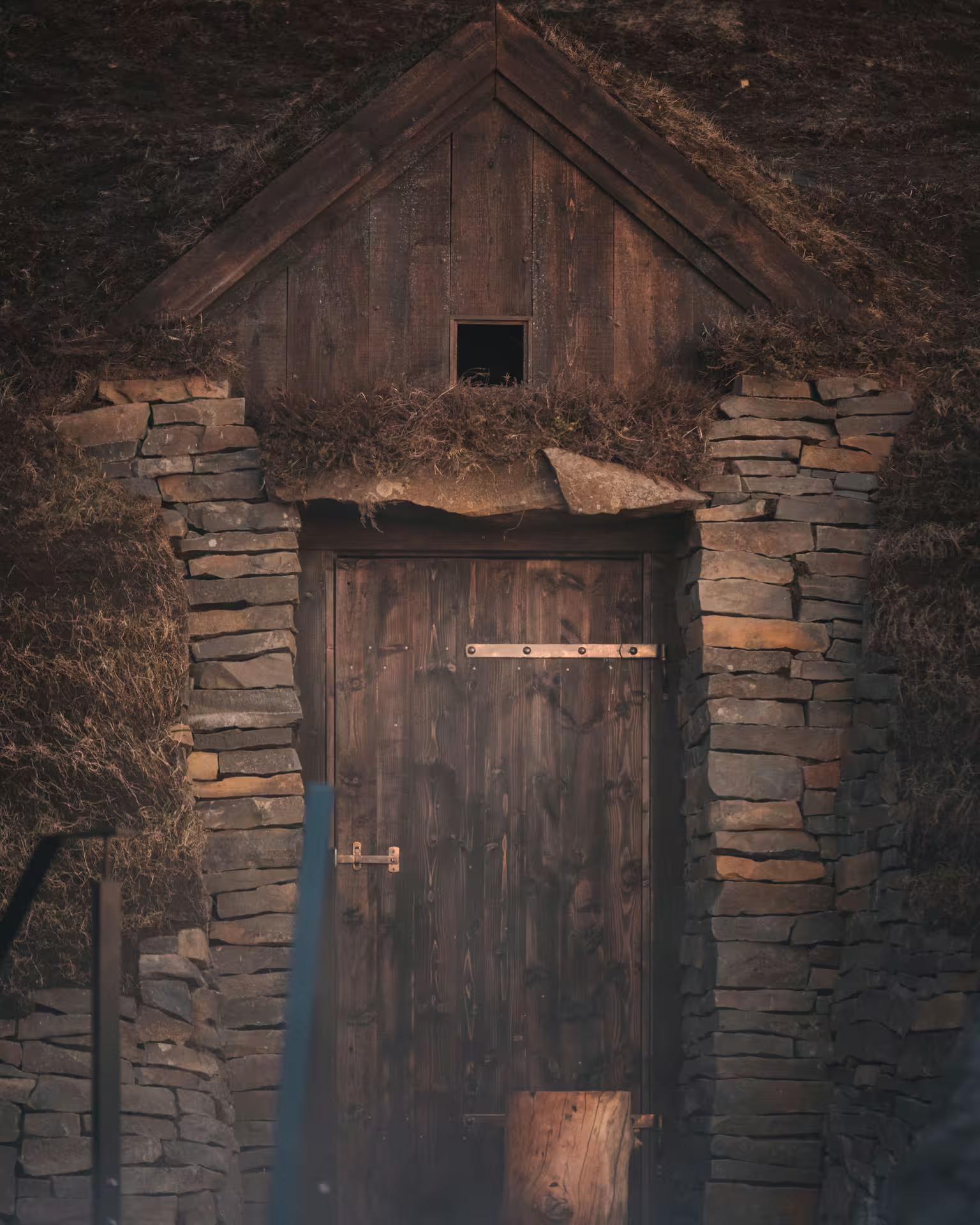 Rustic wooden door at Sky Lagoon's geothermal spa entrance, showcasing Iceland's traditional stone and turf architecture.