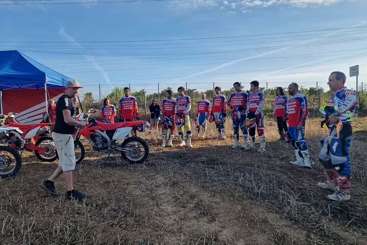Riders gather around dirt bikes under a blue canopy in Lisbon, preparing for a thrilling small group enduro tour.