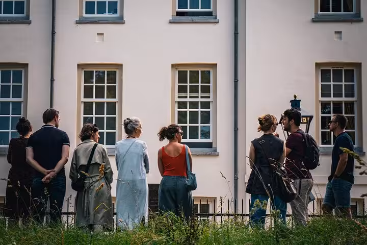 Small-group Utrecht city tour guests listening to a guide by historic courtyard buildings with tall windows