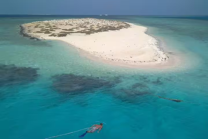 Snorkeler in turquoise Red Sea lagoon near Hamata Island sandbank on VIP boat day trip from Marsa Alam