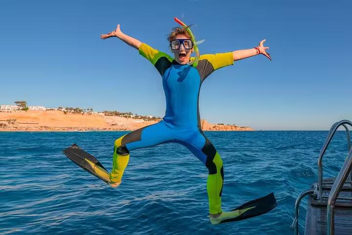 Snorkeler in wetsuit jumping off boat in Red Sea on White Island and Ras Mohamed snorkeling trip from Sharm