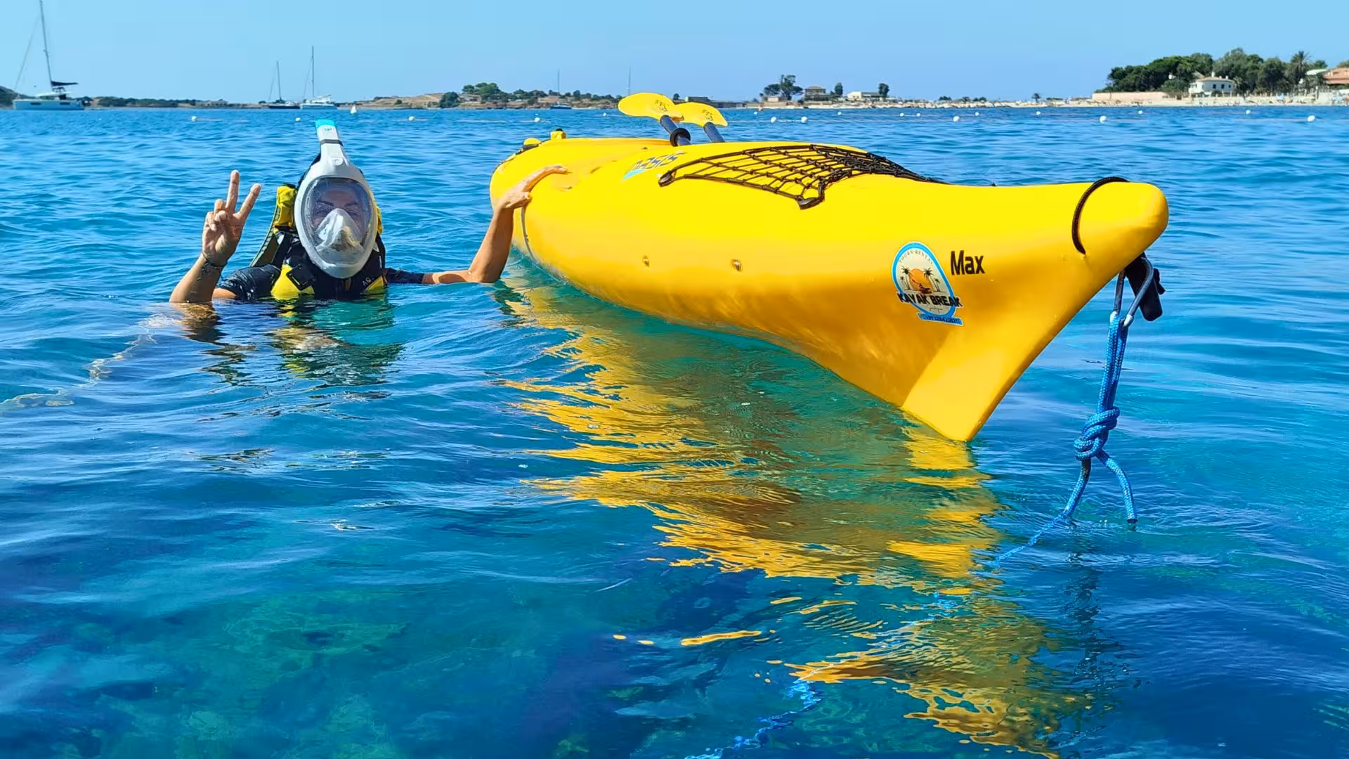 Snorkeler alongside a yellow kayak in clear waters during a Tuerredda kayak tour in Chia.