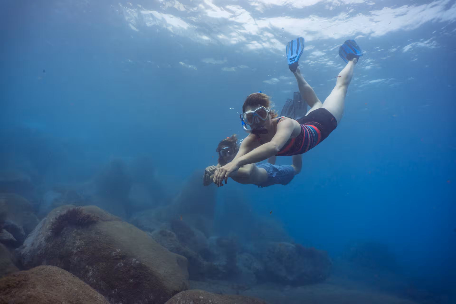 Two snorkelers glide through clear blue waters, exploring vibrant marine life during an eco-park adventure.