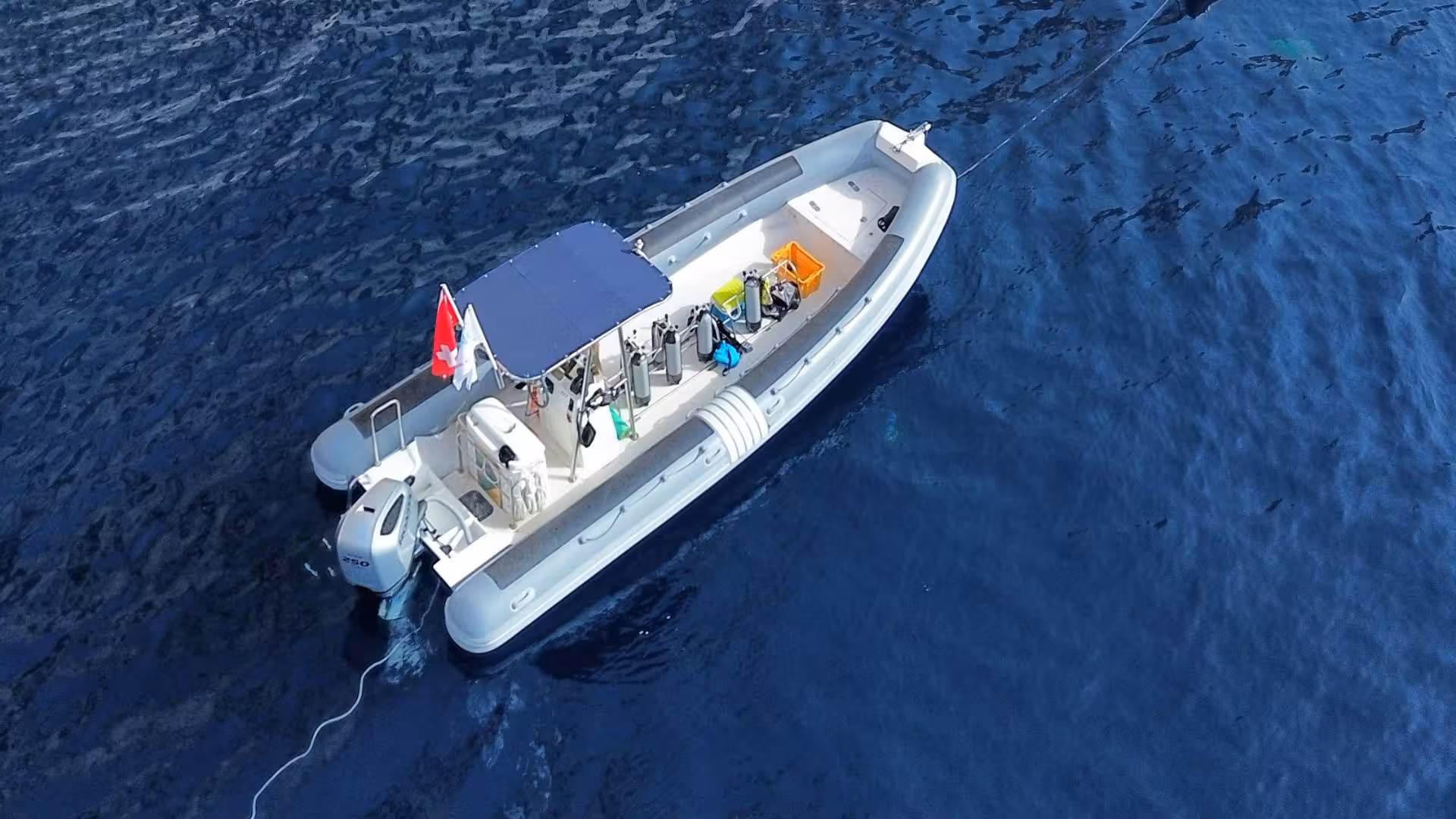 Aerial view of a white snorkeling boat anchored in the deep blue waters near Tavolara Island.