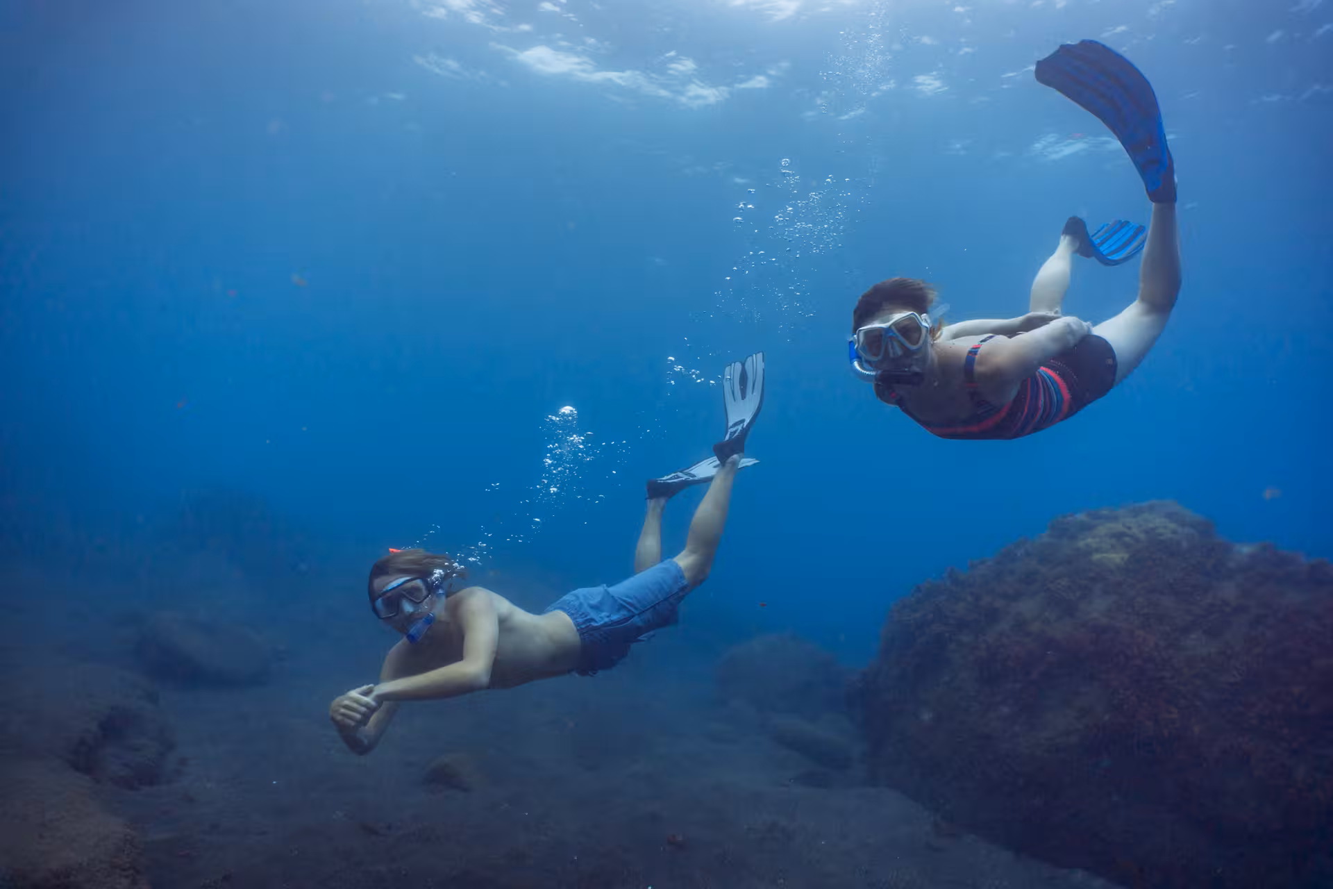 Snorkelers enjoy a thrilling underwater exploration, surrounded by rocks and marine wonders in an eco-park tour.