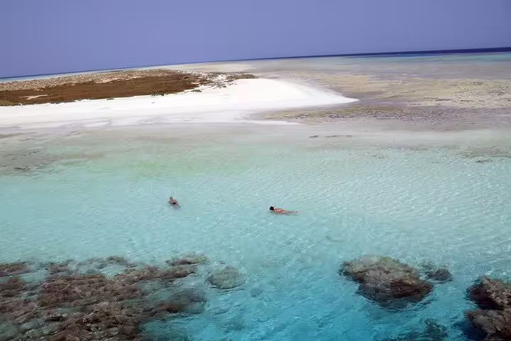 Snorkelers in crystal-clear lagoon near Hamata Island sandbar on VIP boat day trip from Marsa Alam