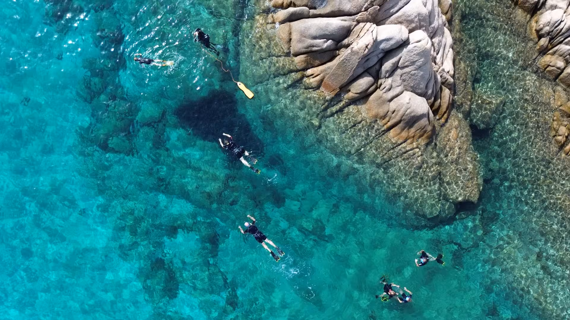 Snorkelers exploring the crystal-clear waters and rocky coastline of Molara, ideal for snorkeling adventures from San Teodoro.
