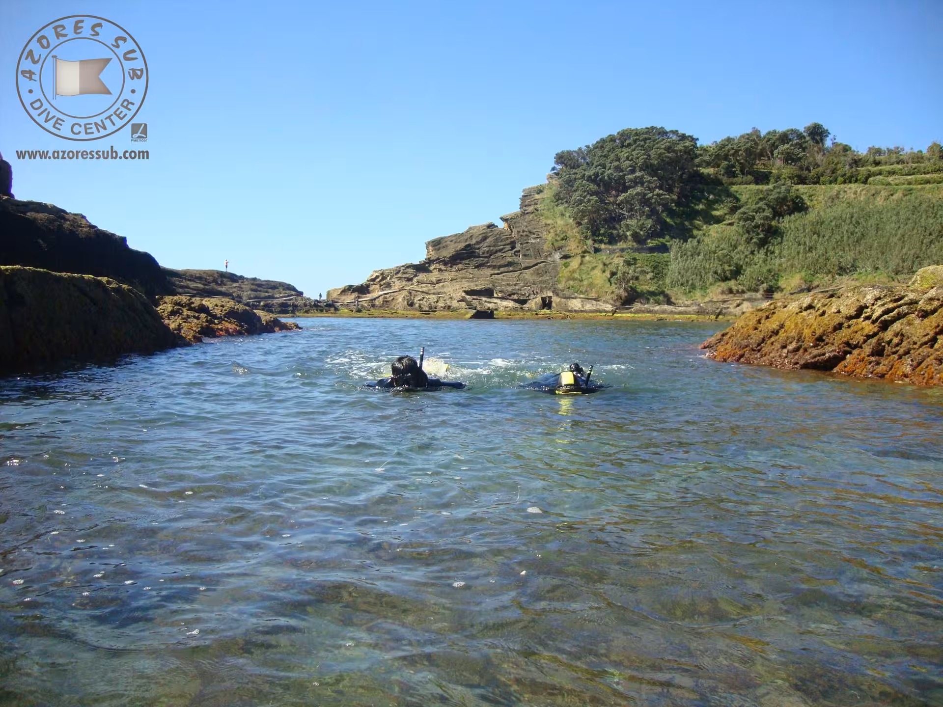 Snorkeling in a calm rocky cove, swimmers heading to shore for an Azores coastal snorkeling adventure