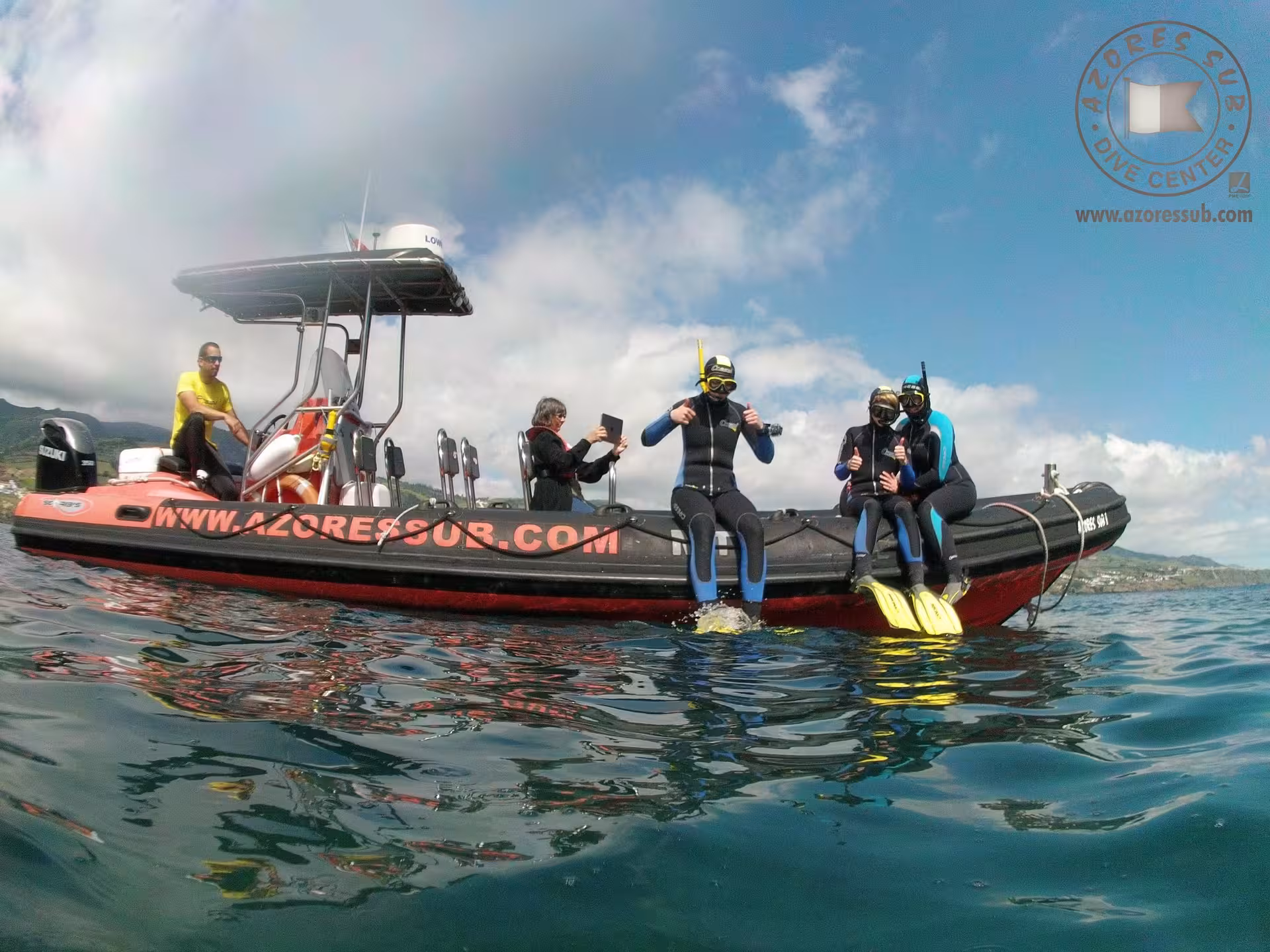 Snorkelers in wetsuits sit on a RIB boat before an Azores snorkeling tour in clear Atlantic waters