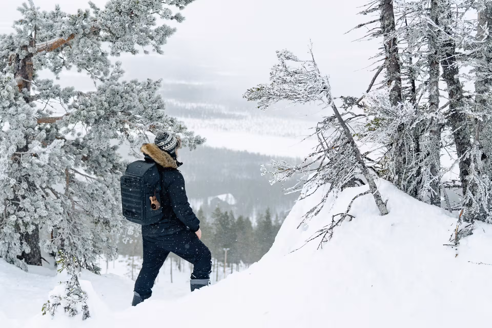 Snowshoer with backpack admiring the snowy landscape and frosted trees in Rovaniemi's Arctic wilderness.