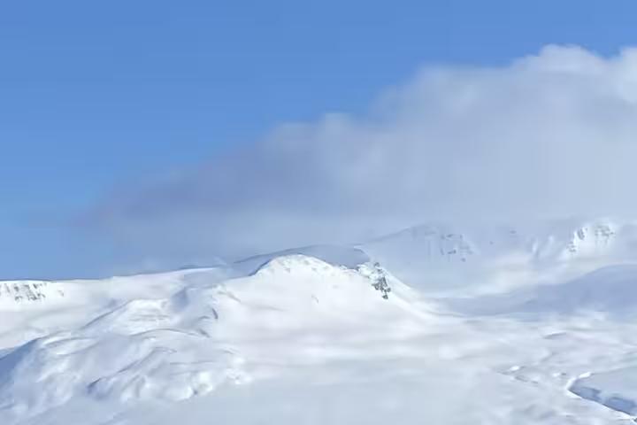 Panoramic snowy mountains in Fljótin, Iceland, on a winter snowshoeing and flotation tour with clear blue sky
