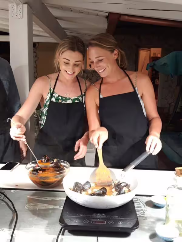 Two guests cook mussels in a Palermo home kitchen during a social cooking and dine with locals experience