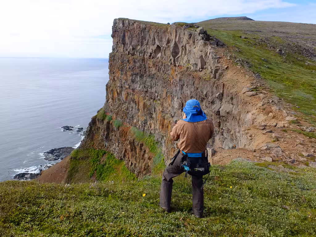 Hiker on rugged sea cliff viewpoint during Solar Eclipse Hike, coastal trail with dramatic ocean panorama