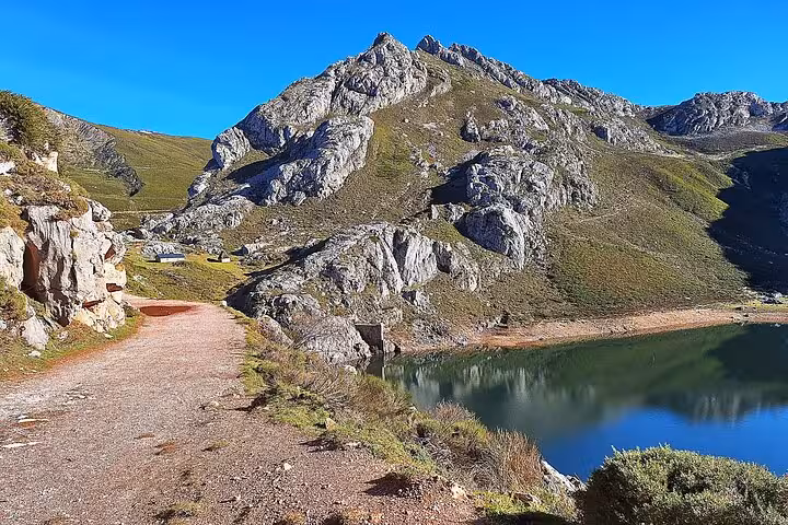 Peaceful hiking trail alongside a serene lake and majestic mountains in Somiedo Natural Park, ideal for guided tours from Oviedo.