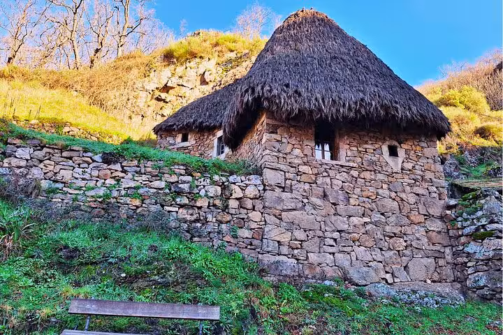 Traditional thatched-roof stone house nestled in Somiedo's vibrant landscape, ideal stop on Oviedo guided tours.