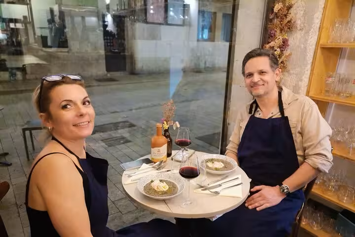 Couple enjoying wine and food pairing at Pce's Vineyard sommelier course, tasting reds with plated dishes indoors