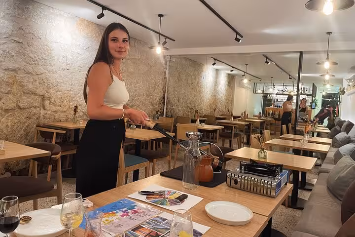 Sommelier prepares port tongs for a 5 Port Wines tasting in a cozy Porto wine bar with stone walls and set tables.