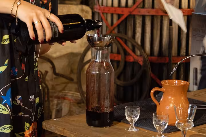 Sommelier pours Douro Valley red into a carafe during Porto wine tasting in a rustic cellar, glasses ready for pairing.