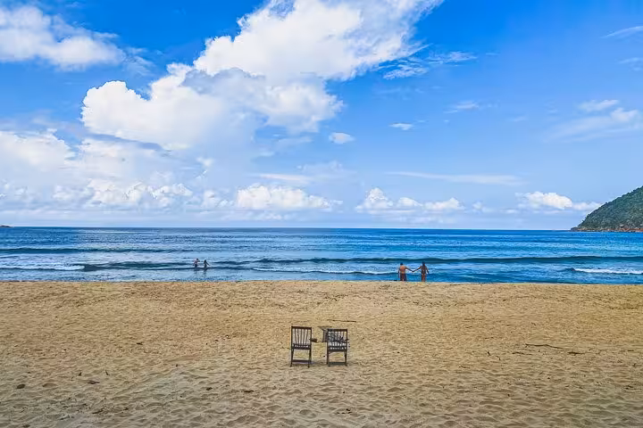 Tranquil Sono Beach with empty chairs and inviting waves under a bright blue sky, ideal for an adventure getaway.