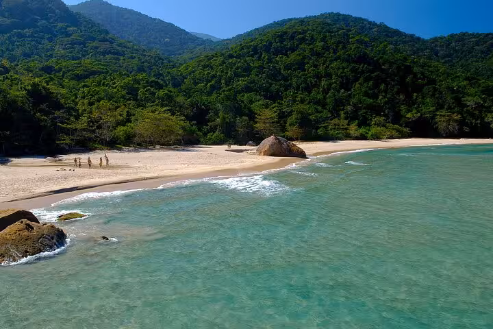 Pristine Sono Beach with turquoise waters and lush green hills on the Paraty Tours adventure.