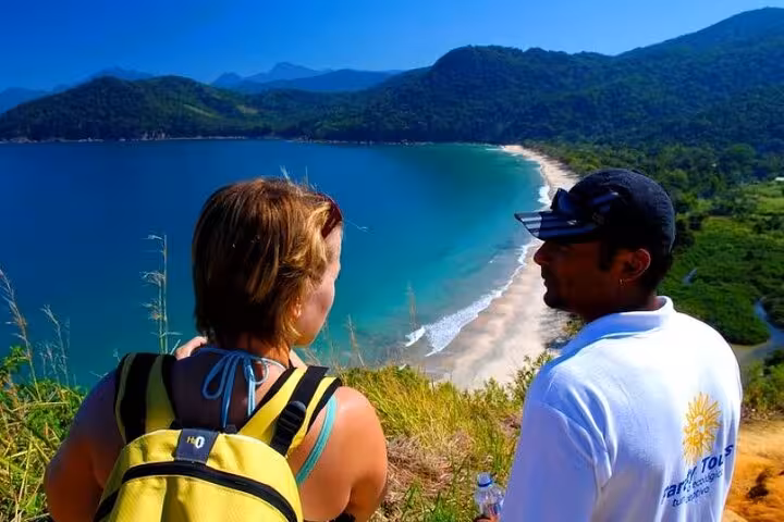 Tour guide and traveler enjoying a scenic view of Sono Beach from a hillside vantage point on a Paraty adventure tour.