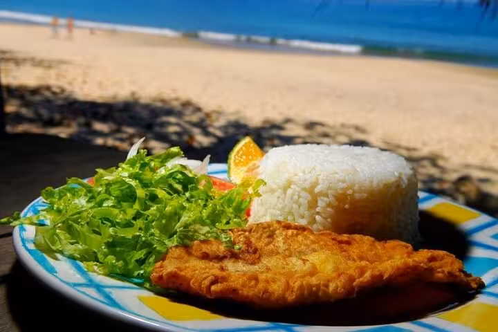 Delicious beachside meal featuring fried fish, rice, and salad at Sono Beach, perfect for a Paraty tour experience.