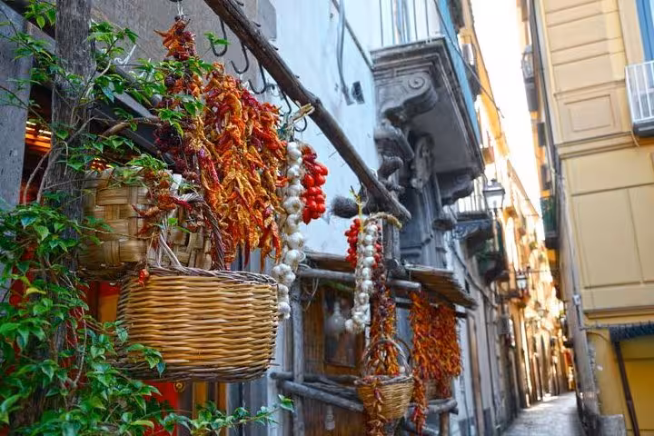 Charming Sorrento alley adorned with hanging baskets of dried chili peppers, garlic, and lush greenery.