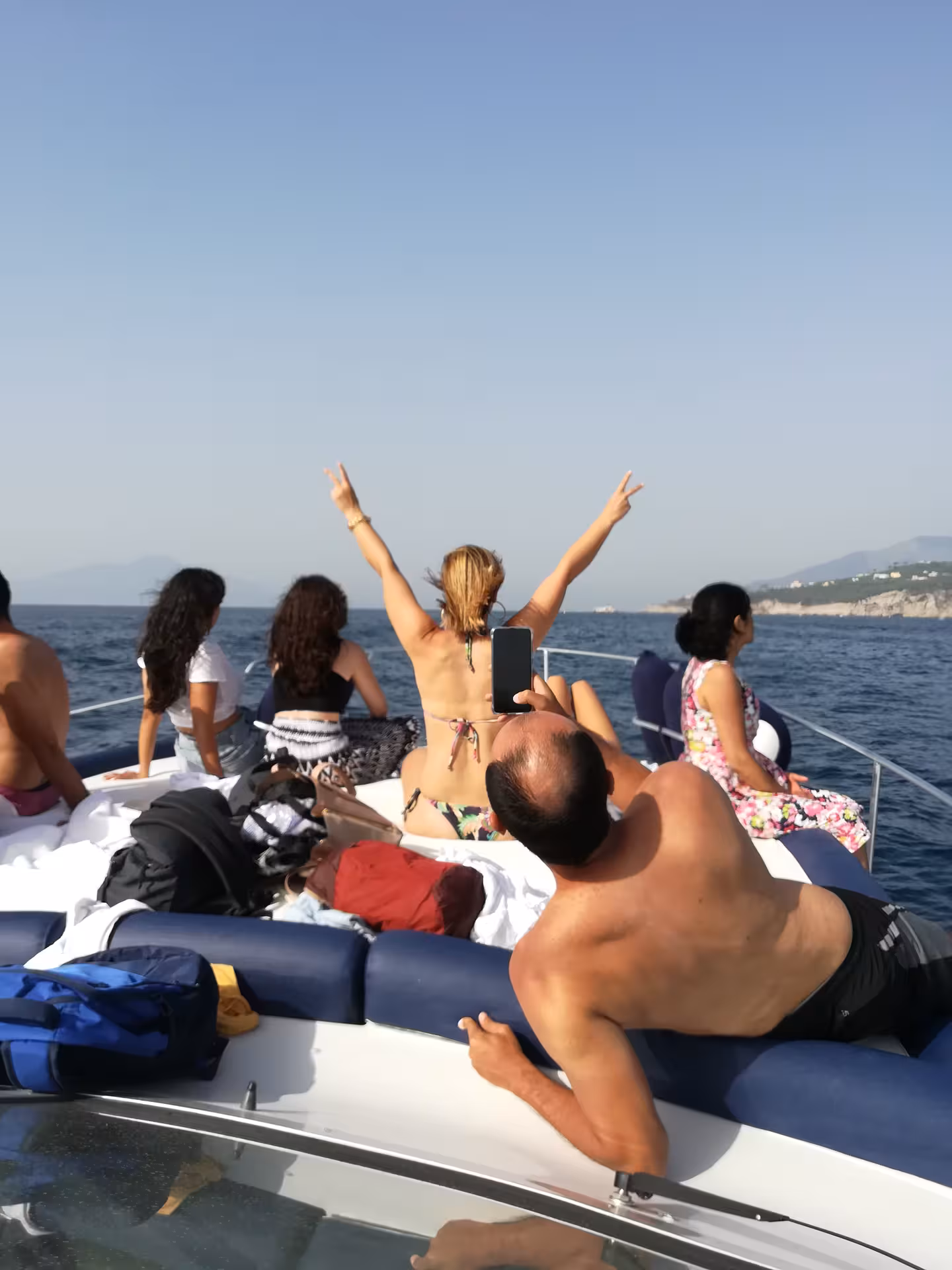 Tourists capturing the stunning coastal view on a boat tour from Sorrento to Amalfi and Positano.