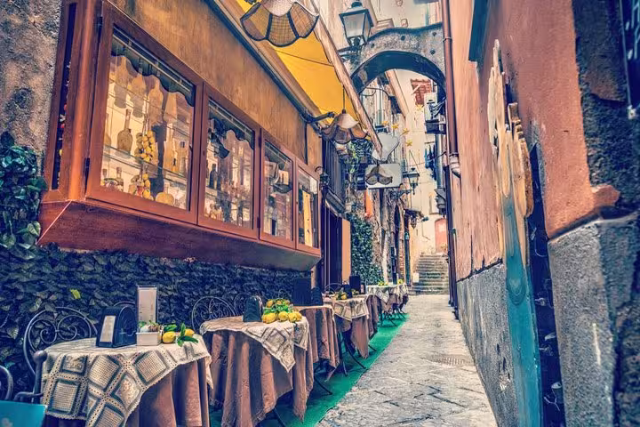 Charming narrow alley in Sorrento featuring inviting outdoor café tables perfect for a relaxing stop on a Naples tour.