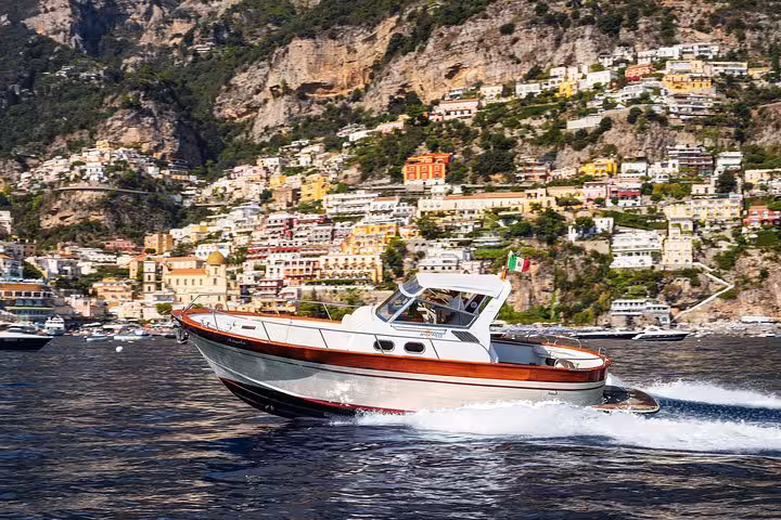 Scenic boat excursion from Sorrento to Capri passing vibrant coastal cliffs and colorful town views.