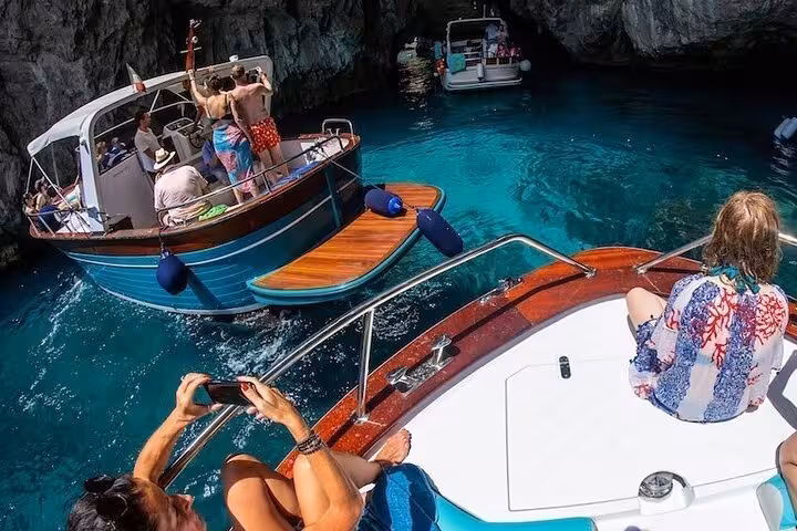 Tourists enjoy a scenic boat ride to the Blue Grotto on a small group tour from Sorrento to Capri.