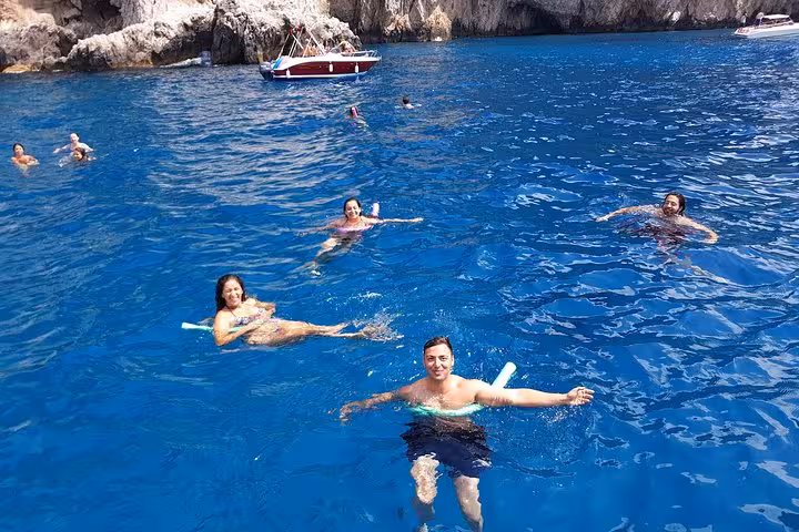 Tourists enjoying a swim in the crystal-clear waters near Capri during a small group boat tour.