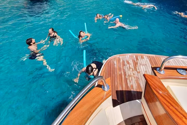 Group swimming in turquoise waters off a Gozzo Apreamare 10 boat during a Sorrento to Capri private tour.