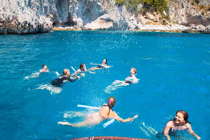 Group enjoying a swim in the vibrant blue waters near Sorrento on a classic Gozzo tour to Capri.