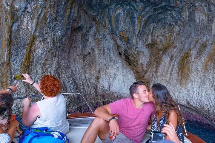 Couple enjoying a romantic moment on a private Gozzo Apreamare 10 boat tour near Capri's scenic caves.