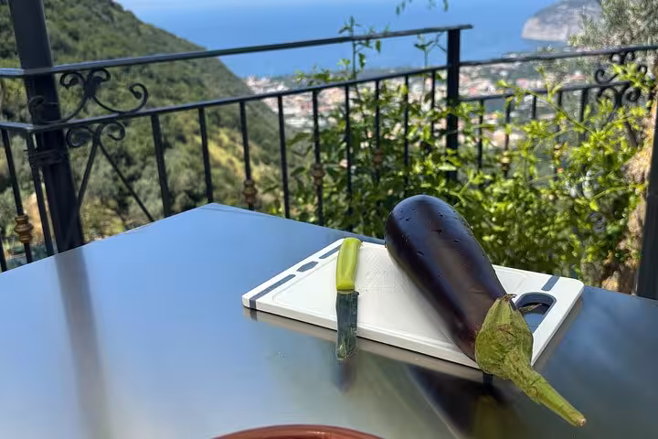 Eggplant on a cutting board with a breathtaking view of Sorrento's coastline from a cooking class terrace.