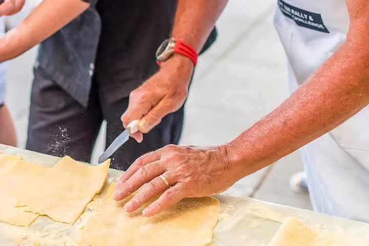 Participant skillfully cuts fresh pasta dough during hands-on cooking class in Sorrento, Italy, focusing on authentic techniques.