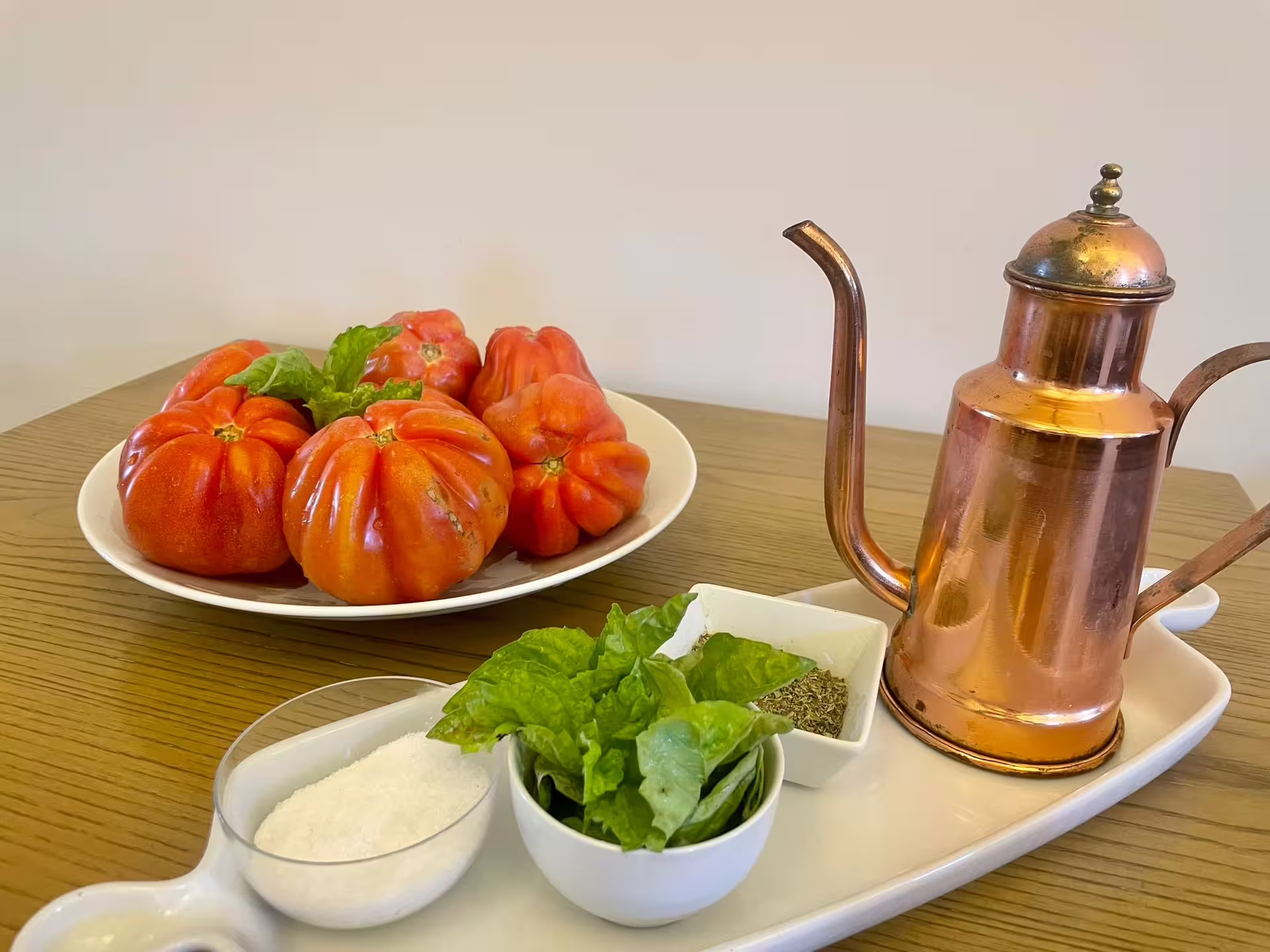 Fresh tomatoes, basil, and spices with a copper oil can on a wooden table at a Sorrento cooking class.