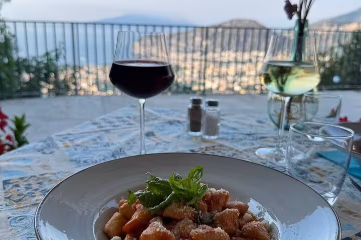 Savor traditional Sorrento gnocchi with wine, overlooking a scenic coastal view during a cooking class with local chef.