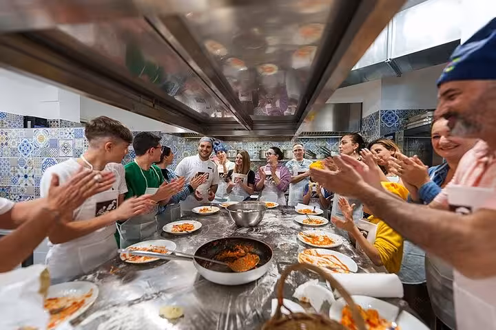 Participants applauding around a table filled with traditional Italian dishes during a cooking class in Sorrento.