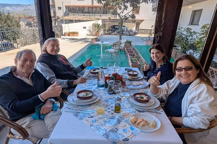 Group enjoying traditional Sorrento lunch prepared in cooking class with local chef, set on an outdoor terrace.