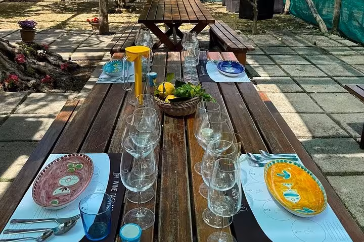 Rustic outdoor dining setup with colorful plates and wine glasses ready for a traditional Sorrento lunch.