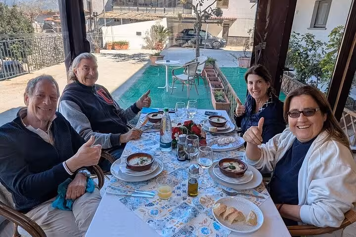 Group enjoying a farm-to-table meal outdoors, savoring traditional dishes at an authentic pizza and cheese experience.