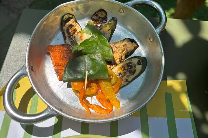 A dish of grilled vegetables and lemon leaves on a sunny table, showcasing local flavors for a Sorrento tasting tour.