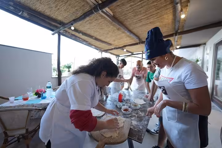 Group of people crafting pizza dough at a farm-to-table cooking class, showcasing hands-on culinary experience.