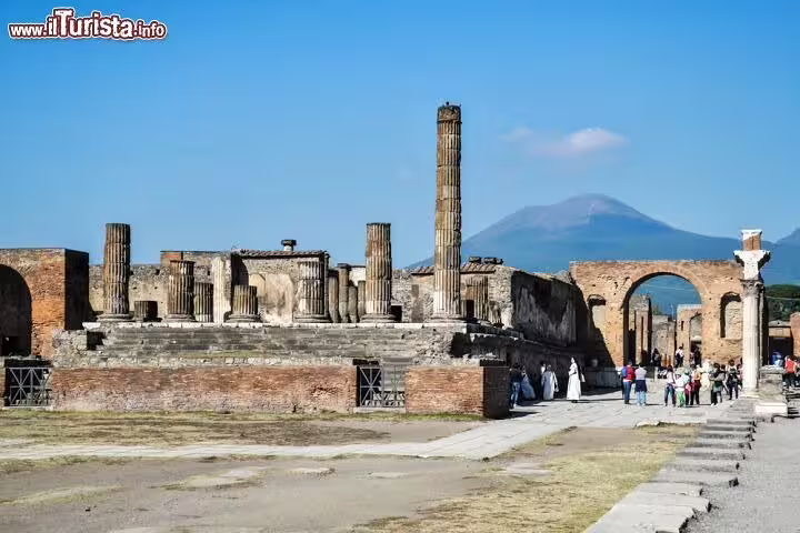 Guided tour group exploring ancient Pompeii ruins with Mount Vesuvius in the background on a Sorrento Positano day trip