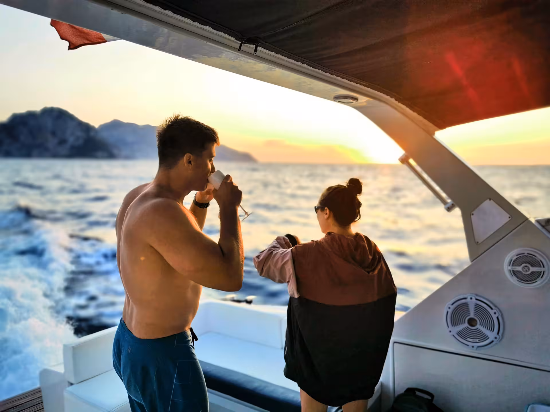Couple enjoys drinks on a boat at sunset, capturing the essence of the Sorrento Small Group Sunset Boat Experience.