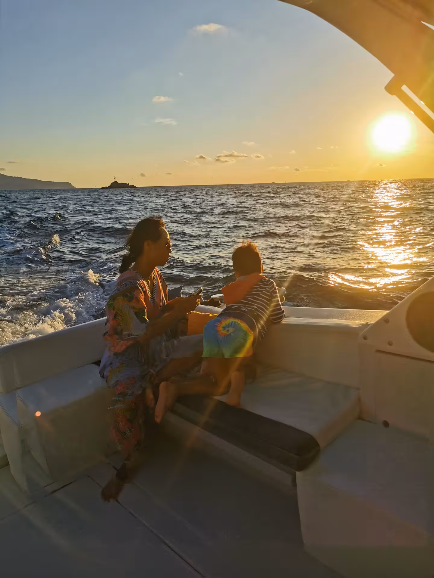 Mother and child on a Sorrento sunset boat cruise, taking in the serene ocean views and golden sky.