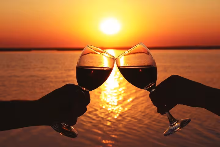 Romantic sunset aperitif with wine glasses clinking against a golden sea backdrop in Sorrento.